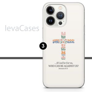 Op de afbeelding: Witte iPhone-hoes met een bloemig kruisontwerp en de quote "...Als God voor ons is, wie kan dan tegen ons zijn? Romeinen 8:31".
