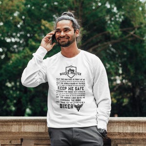 May include: White long-sleeve shirt with a black print that reads "Bikers Prayer" and includes a motorcycle graphic. The text includes the phrase "Keep Me Safe".