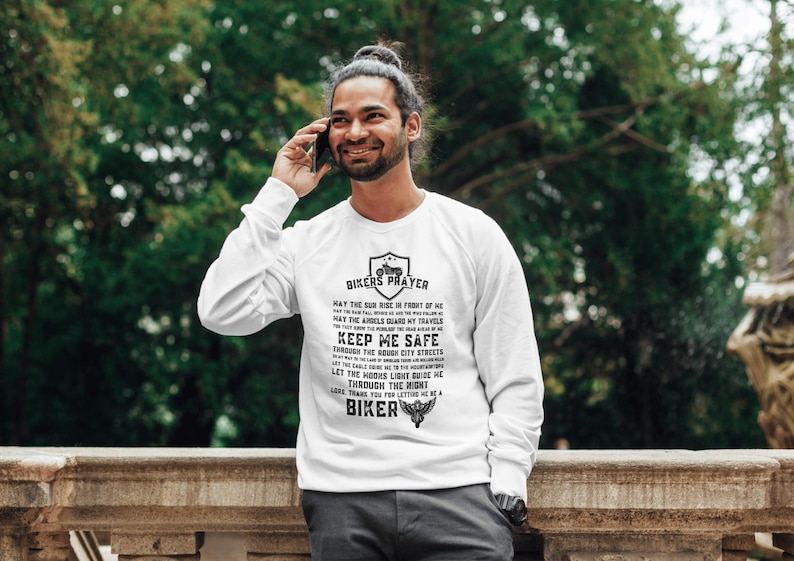 May include: White long-sleeve shirt with a black print that reads "Bikers Prayer" and includes a motorcycle graphic. The text includes the phrase "Keep Me Safe".
