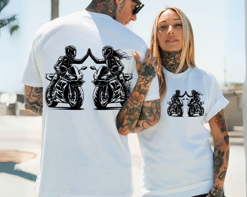 May include: Two white t-shirts with a black graphic of two people riding motorcycles and high-fiving each other.