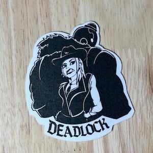 May include: Black and white sticker featuring a cowgirl with a stern expression, wearing a hat and vest. A large, shadowy figure looms behind her. The word "DEADLOCK" is printed in a stylized font below the image.
