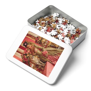 May include: A white puzzle box with an open lid revealing a completed puzzle image and loose puzzle pieces. The image shows a person in a leopard print dress with a cheetah. The puzzle pieces are various colors.