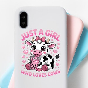 May include: White phone case with a cartoon cow design. The cow has a pink bow and is drinking boba tea. Pink text reads "JUST A GIRL WHO LOVES COWS". Pink hearts are scattered around the cow.