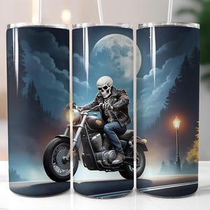 Peut inclure: Un gobelet en acier inoxydable avec un motif de squelette conduisant une moto sous une pleine lune. L'arrière-plan est bleu foncé avec des nuages blancs et des arbres.