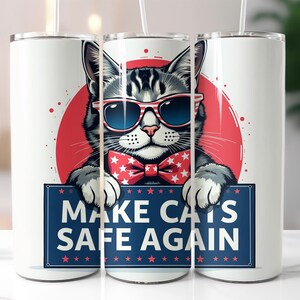 Może przedstawiać: Biały kubek z kreskówkowym kotem w okularach przeciwsłonecznych i muszce, na tle czerwonego koła. Kot trzyma znak z napisem "MAKE CATS SAFE AGAIN" w kolorze niebieskim i białym.