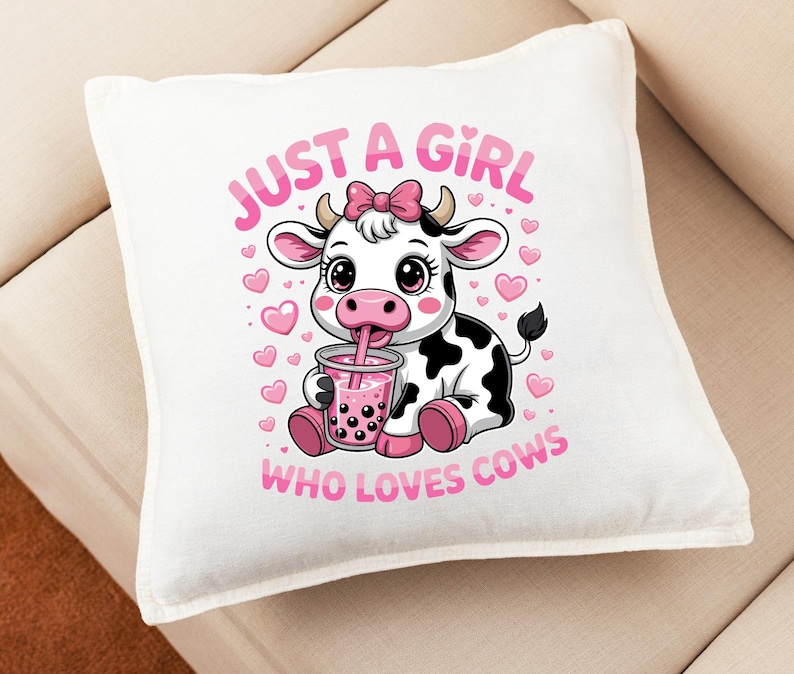 May include: Square white cushion featuring a cartoon cow design. The cow is black and white with a pink bow, drinking from a pink drink. The text reads "JUST A GIRL WHO LOVES COWS" in pink.