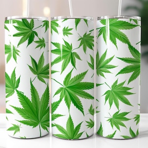 May include: Three white insulated tumblers with a repeating pattern of bright green cannabis leaves. The leaves vary in size and are set against a clean white background. Each tumbler has a clear straw.