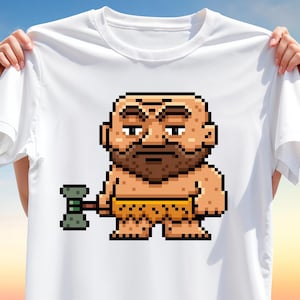 May include: White t-shirt featuring a pixelated cartoon of a bald, bearded man holding a green and gray hammer. The man is wearing a yellow loincloth. The design is centered on the shirt.