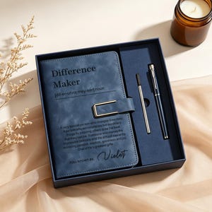 Può includere: Un taccuino blu navy con una chiusura in metallo dorato e il testo Difference Maker, una definizione e il nome Violet stampati sulla copertina. Il taccuino è in una scatola abbinata con una penna nera e una ricarica incluse.