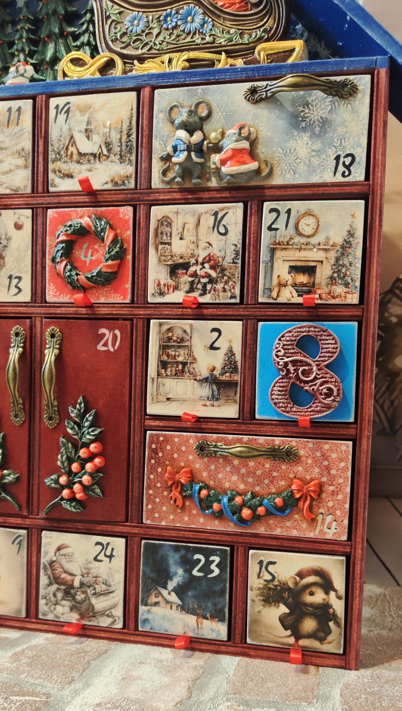 Puede incluir: Un calendario de adviento de madera con m&uacute;ltiples cajones que presentan ilustraciones navide&ntilde;as, incluyendo ratones, Santa Claus y paisajes invernales. Cada caj&oacute;n est&aacute; numerado y algunos muestran elementos decorativos en relieve como coronas y bayas.