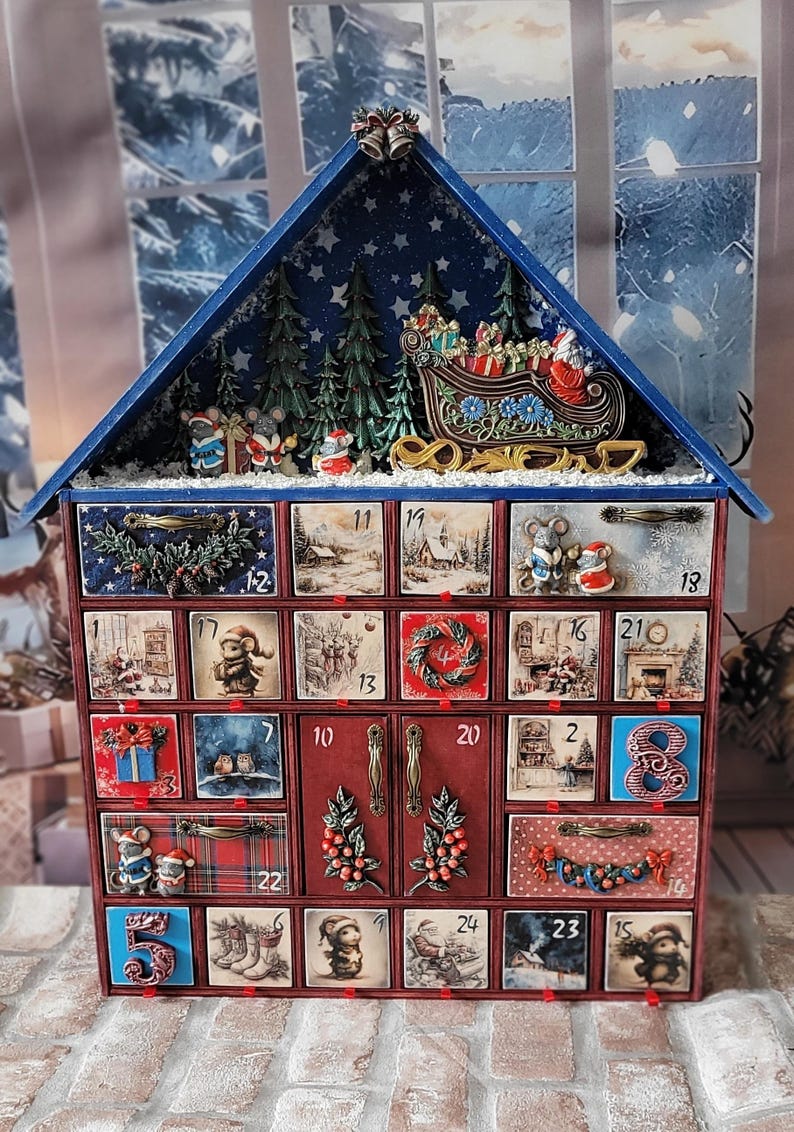 Puede incluir: Un calendario de adviento de madera con forma de casa y veinticuatro cajones numerados. El techo presenta un trineo en miniatura, a Santa Claus y pinos. Cada caj&oacute;n muestra ilustraciones navide&ntilde;as, relieves decorativos y tiradores met&aacute;licos.