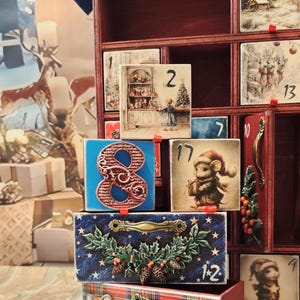 Puede incluir: Un calendario de adviento de madera con m&uacute;ltiples cajones que presentan ilustraciones festivas de ratones, escenas invernales y acebo. Los cajones est&aacute;n numerados, incluyendo 1, 2, 7, 8, 10, 11, 13, 17, 22 y 12. Algunos cajones tienen tiradores de metal, mientras que otros est&aacute;n decorados con figuras de ratones y patrones de cuadros.