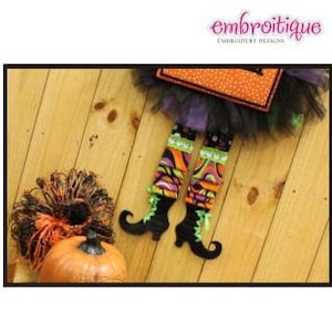 May include: A witch's legs with black tulle skirt, green and black shoes, and colorful striped stockings. The legs are attached to a door hanger with a black and orange pumpkin design.
