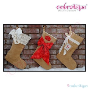 May include: Three burlap Christmas stockings hanging on a brick wall. The stocking on the left has a white ruffle and bow. The middle stocking has a red and white polka dot bow. The stocking on the right has a white ribbon and a burlap tag with the letter "D" on it.