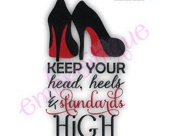 May include: An embroidery design featuring two black high-heeled shoes with red soles. Below the shoes, the text reads: KEEP YOUR head, heels & standards HIGH. The words are in a mix of black block letters and red cursive script.