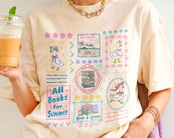 May include: Ivory-colored t-shirt with a whimsical design featuring ducks, books, and the text "All Books for Summer." The shirt also includes the text "Beach Book Club" and "Books & Coffee."