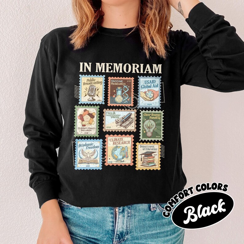 May include: Black long-sleeve shirt with a stamp design. The stamps feature various themes, including "Public Broadcasting," "Vaccine Research," and "Climate Research." The shirt also has the words "IN MEMORIAM" and "COMFORT COLORS Black."
