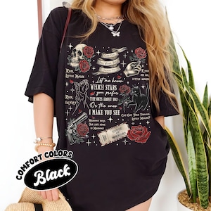 Puede incluir: Camiseta negra con un estampado gr&aacute;fico de una calavera, rosas, estrellas y un texto que dice "Let me know which stars you prefer, the ones above you or the ones I make you see". El texto est&aacute; rodeado de una variedad de otras im&aacute;genes, incluyendo un gato, un arma de fuego y un boleto que dice "House of Mirrors".