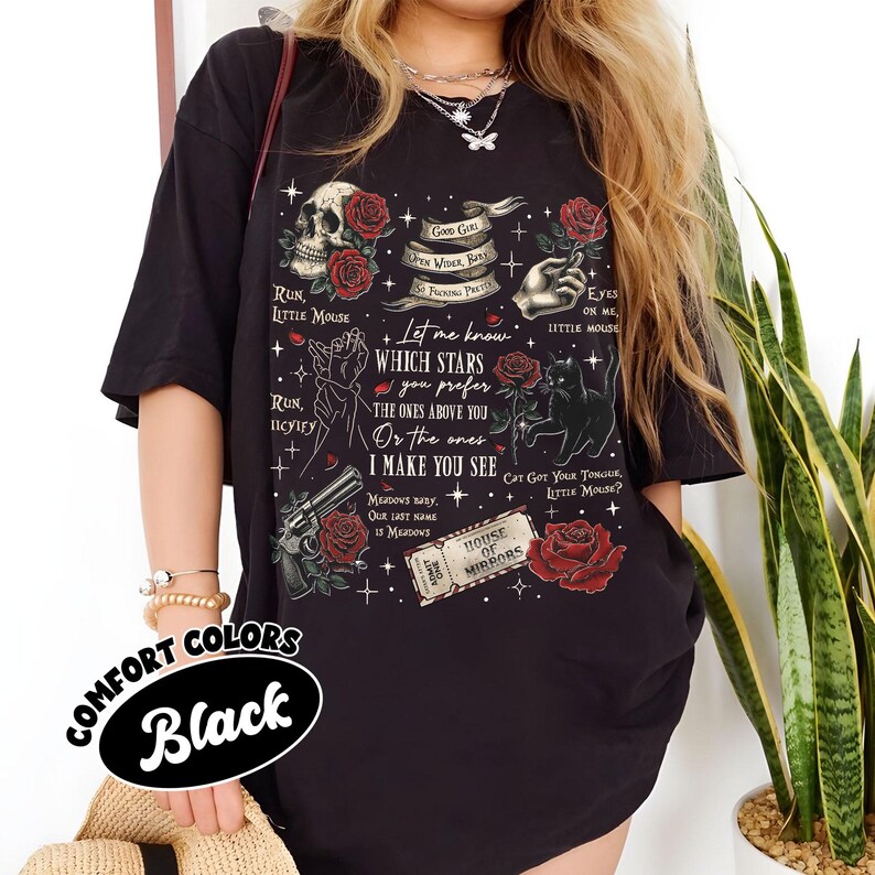 Puede incluir: Camiseta negra con un estampado gr&aacute;fico de una calavera, rosas, estrellas y un texto que dice "Let me know which stars you prefer, the ones above you or the ones I make you see". El texto est&aacute; rodeado de una variedad de otras im&aacute;genes, incluyendo un gato, un arma de fuego y un boleto que dice "House of Mirrors".