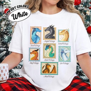 May include: White t-shirt featuring colorful dragon illustrations within postage stamp-style frames. The shirt includes the text "COMFORT COLORS" and "White" in a circular design. Each stamp showcases a different dragon type, such as "SeaWings" and "NightWings".
