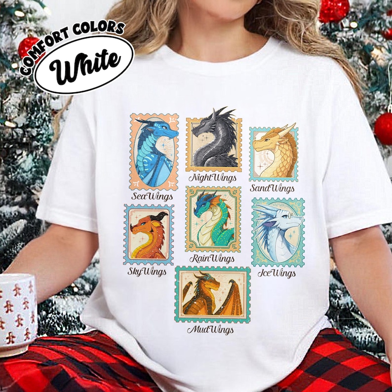May include: White t-shirt featuring colorful dragon illustrations within postage stamp-style frames. The shirt includes the text "COMFORT COLORS" and "White" in a circular design. Each stamp showcases a different dragon type, such as "SeaWings" and "NightWings".