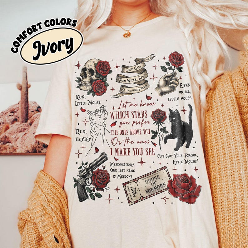 Puede incluir: Camiseta de color marfil con un estampado gr&aacute;fico de una calavera, rosas, estrellas, un gato, una pistola y un texto que dice "Let me know which stars you prefer the ones above you or the ones I make you see".