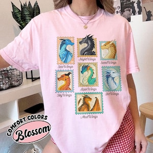 May include: A light pink Comfort Colors Blossom t-shirt featuring nine dragon illustrations in postage stamp designs. Each stamp showcases a different dragon type, including SeaWings, NightWings, and SandWings.