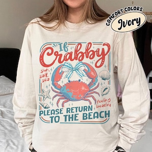 May include: Ivory long-sleeve shirt with a crab graphic. The graphic includes the text "If Crabby, Please Return to the Beach" with a crab, seashells, and starfish. The shirt is a Comfort Colors brand.