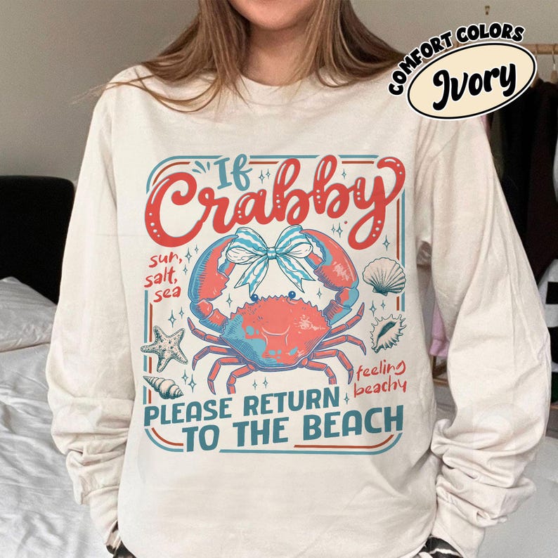 May include: Ivory long-sleeve shirt with a crab graphic. The graphic includes the text "If Crabby, Please Return to the Beach" with a crab, seashells, and starfish. The shirt is a Comfort Colors brand.