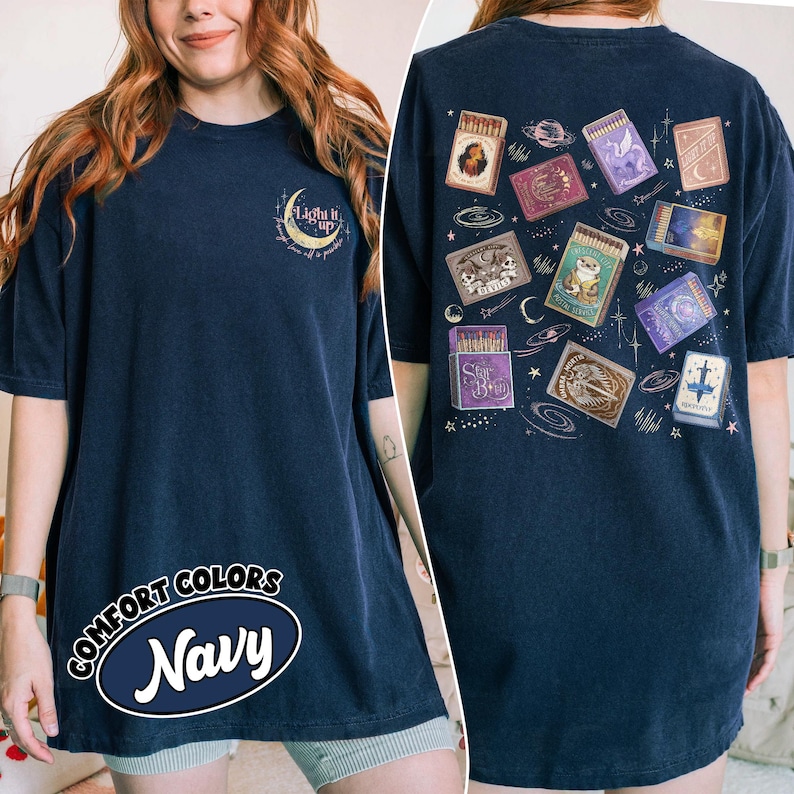 May include: Navy blue Comfort Colors t-shirt with a crescent moon and text that reads "Light it up". The back of the shirt features various matchbox designs with celestial and fantasy themes.