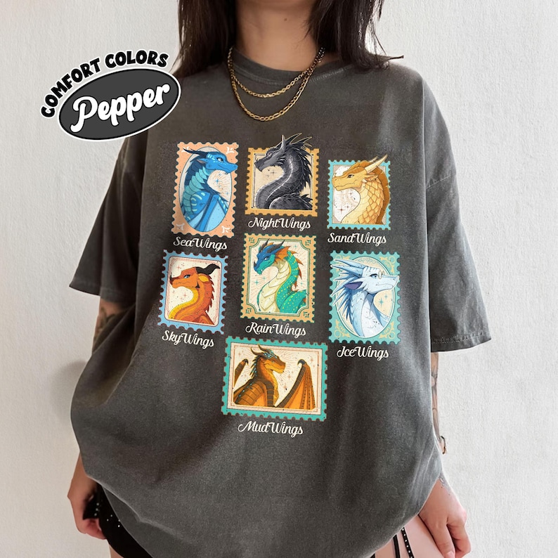 May include: Dark grey t-shirt featuring a collection of dragon illustrations in postage stamp designs. The stamps showcase various dragon types with names like SeaWings, NightWings, and SandWings. The shirt has the text "COMFORT COLORS Pepper".