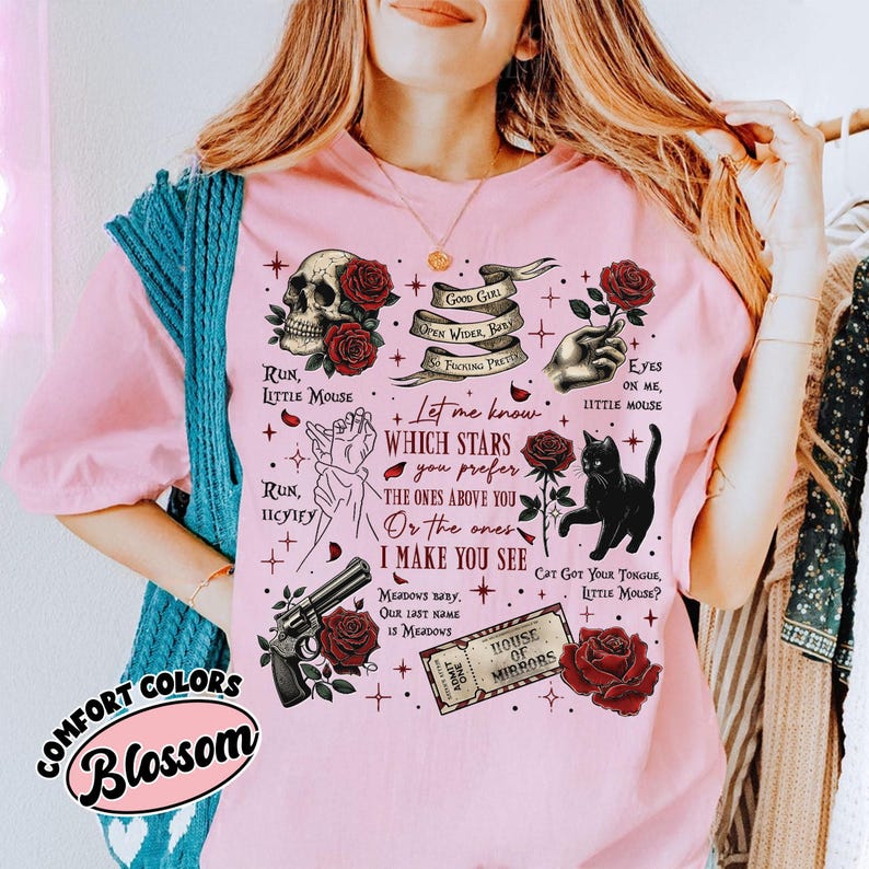 Puede incluir: Camiseta rosa con un estampado gr&aacute;fico de rosas, calaveras, estrellas y otros s&iacute;mbolos. El texto en la camiseta dice "Good Girl Open Wider, Baby, So Facing Pretty", "Run, Little Mouse", "Run, Icy Icey", "Let me know which stars you prefer the ones above you or the ones I make you see", "Eyes on me, Little Mouse", "Cat Got Your Tongue, Little Mouse?", "Meadows Baby, Our Last Name Is Meadows", "House of Mirrors".