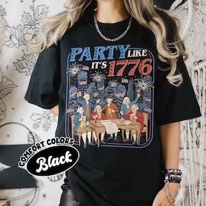 Puede incluir: Camiseta negra con un gr&aacute;fico que dice "PARTY LIKE IT'S 1776". El gr&aacute;fico presenta una ilustraci&oacute;n de figuras hist&oacute;ricas celebrando con fuegos artificiales y banderas. La camiseta tambi&eacute;n tiene las palabras "COMFORT COLORS" y "Black".