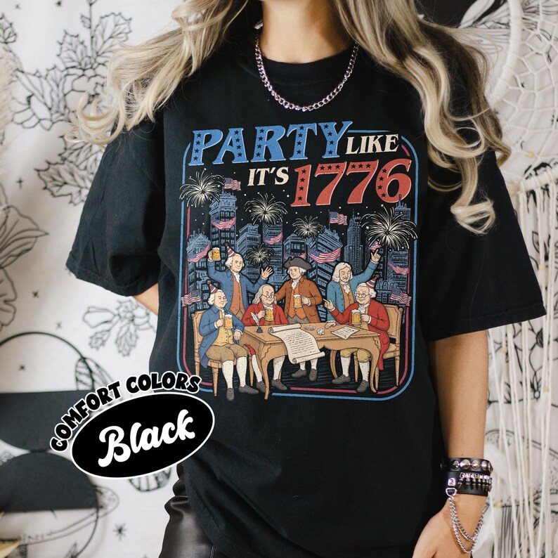 Puede incluir: Camiseta negra con un gr&aacute;fico que dice "PARTY LIKE IT'S 1776". El gr&aacute;fico presenta una ilustraci&oacute;n de figuras hist&oacute;ricas celebrando con fuegos artificiales y banderas. La camiseta tambi&eacute;n tiene las palabras "COMFORT COLORS" y "Black".
