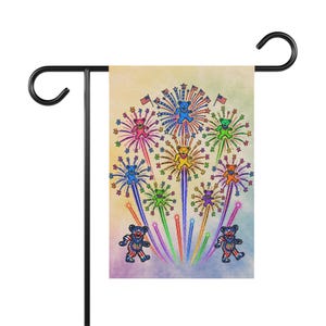 May include: A rectangular garden flag featuring a colorful illustration of dancing bears integrated into firework bursts. The design includes small American flags, vibrant star shapes, and two larger bears at the bottom wearing patriotic red, white, and blue patterns.