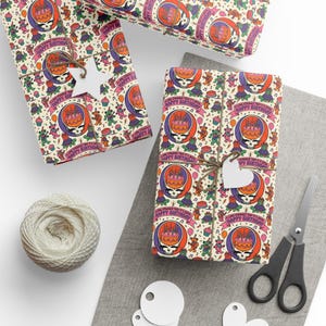 May include: Birthday gift wrap with a repeating pattern of a skull with a cake, dancing bears, and the text "Happy Birthday." The gifts are tied with twine and have white heart-shaped tags. A ball of twine and scissors are also present.