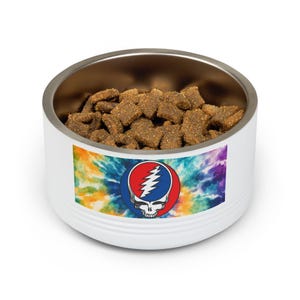 May include: A white pet bowl with a stainless steel interior, filled with dry pet food. The bowl features a tie-dye design with a Steal Your Face logo. The logo is a skull with a lightning bolt.