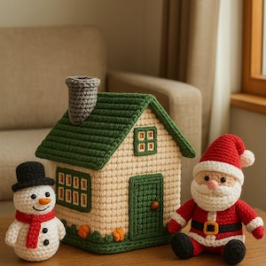 Könnte beinhalten: Gehäkelte Weihnachtsdekorationen, darunter ein Haus mit grünem Dach, ein Schneemann mit schwarzem Hut und rotem Schal sowie eine Weihnachtsmannfigur im roten Anzug. Das Haus hat einen beigen Körper und eine grüne Tür.