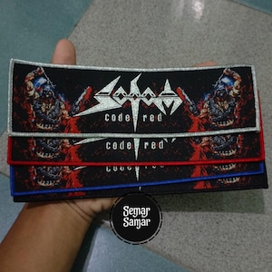 May include: Three rectangular patches with the text "Sodom Code Red" in silver and white. The patches have a black background with red and white accents. The top patch has a silver border, the middle patch has a red border, and the bottom patch has a blue border.