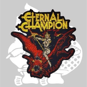 Puede incluir: Un parche bordado negro y rojo con el texto "Eternal Champion" en purpurina dorada. El parche presenta a una mujer montando un demonio alado.