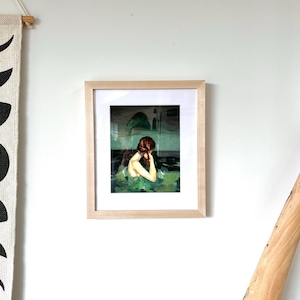 a framed painting of a woman with a pensive expression, hanging on a white wall.