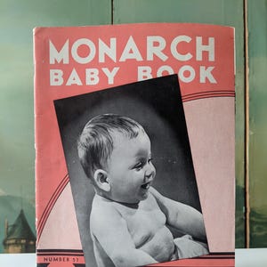 May include: A pink and white booklet titled "Monarch Baby Book" with a black and white photo of a baby on the cover. The booklet is number 57 and costs 25 cents. The text "Published by the makers of...Monarch Yarns" is printed on the bottom of the cover.