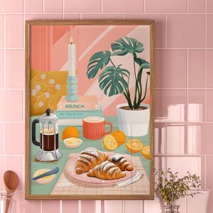 Puede incluir: Una ilustración enmarcada de una escena de desayuno con croissants, una cafetera de prensa francesa, una taza de café, limones y una vela sobre un mantel a cuadros. El texto del libro dice "BRUNCH AT THE BISTRO".