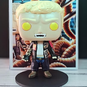 May include: A custom-made Pop! figure of a character with blonde hair, wearing a black leather jacket with a leopard print sleeve, blue jeans, and a white shirt. The figure has yellow eyes and fangs. The figure is standing on a black base. The figure is in front of a box with the Pop! logo and the number 08.