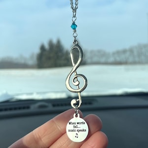 May include: A silver car charm with a treble clef design and a round charm that reads "When words fail... music speaks".