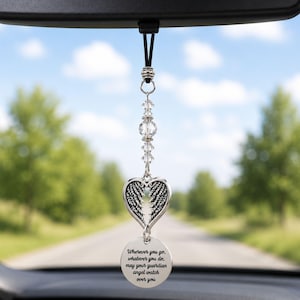 May include: A car rearview mirror hanging ornament featuring a silver-toned heart with angel wing detailing, clear faceted crystal beads, and a round metal charm engraved with the text: Wherever you go, whatever you do, may your guardian angel watch over you.