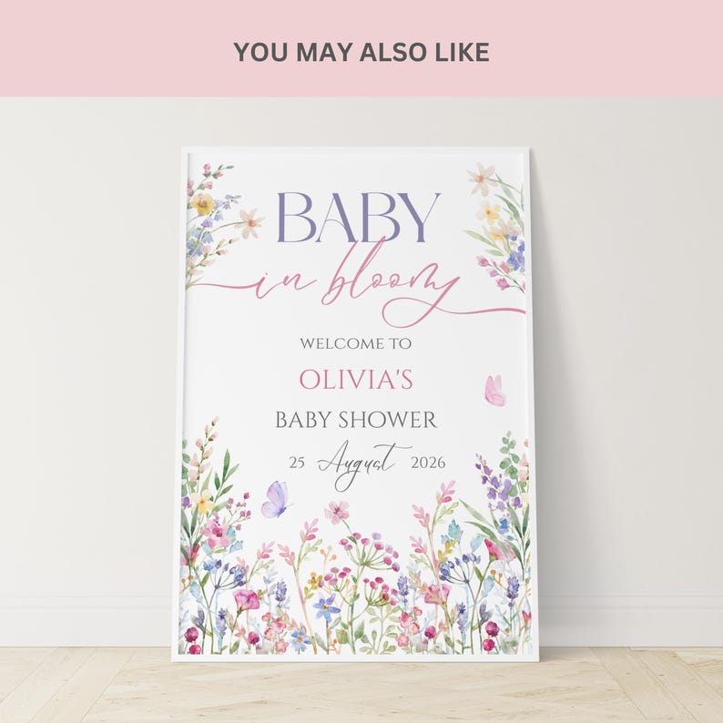 May include: A framed baby shower sign with floral watercolor illustrations. The sign reads "BABY in bloom" and welcomes guests to Olivia's baby shower on August 25, 2026. The design features pastel colors and butterflies.