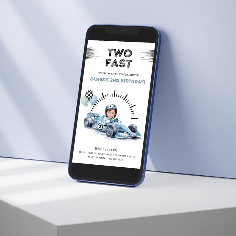 May include: A smartphone displaying a digital birthday invitation with the text TWO FAST, SPEED ON OVER TO CELEBRATE JAMES'S 2ND BIRTHDAY, featuring a child in a racing helmet driving a light blue race car, balloons, and event details.