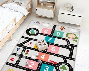 May include: A children's play mat with a road and number design. The mat features a road network with numbers, trees, houses, and a hot air balloon. A wooden toy box and small animal figures are on the mat.