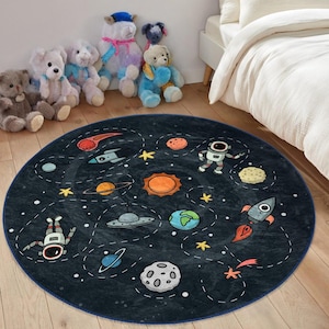 May include: A round, blue and black space-themed rug with a variety of planets, stars, rockets, and astronauts. The rug is perfect for a child's room or play area.